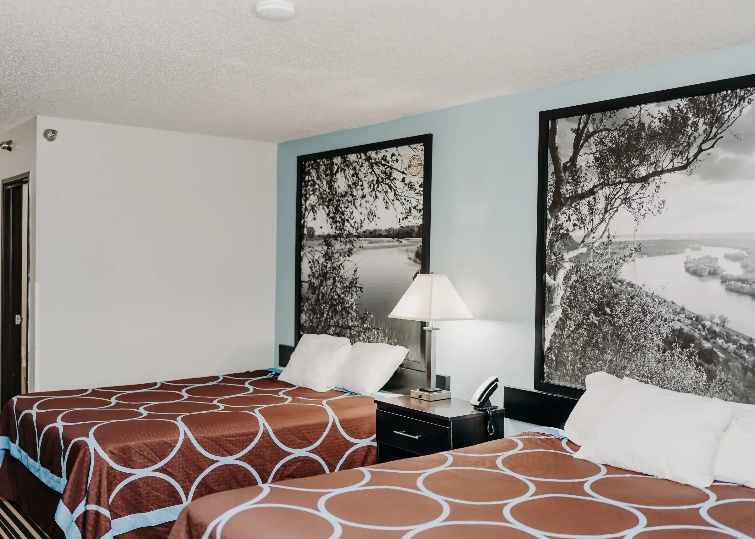 Both queen beds in a standard double room, under framed prints of the Minnesota river valley
