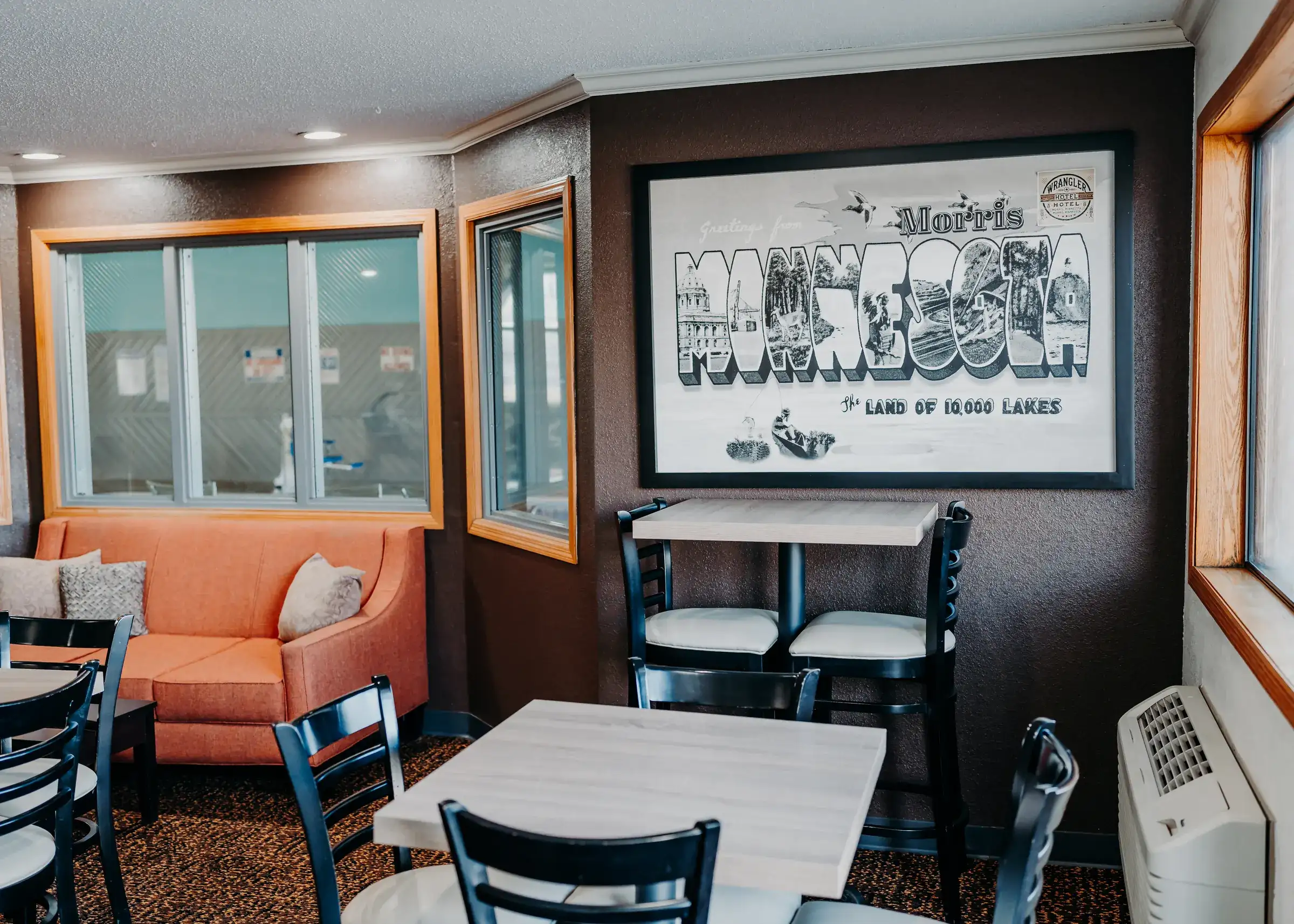 Breakfast seating beneath a hand-drawn "Greetings from Morris, Minnesota" postcard mural